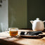 IKEA 365+ glass mug of tea beside a white teapot on a wooden table